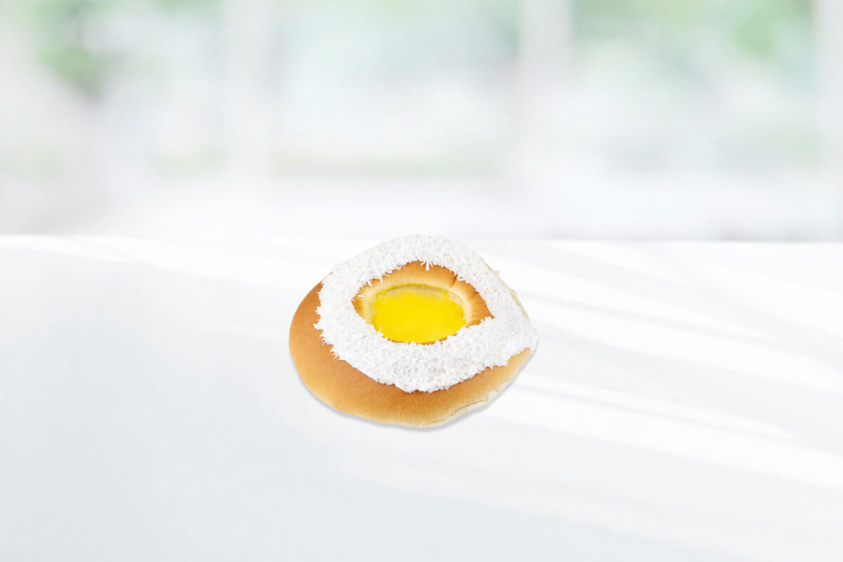 Skolebrød pyntet med hvit melisglasur med kokosmasse og gul vaniljeplomme